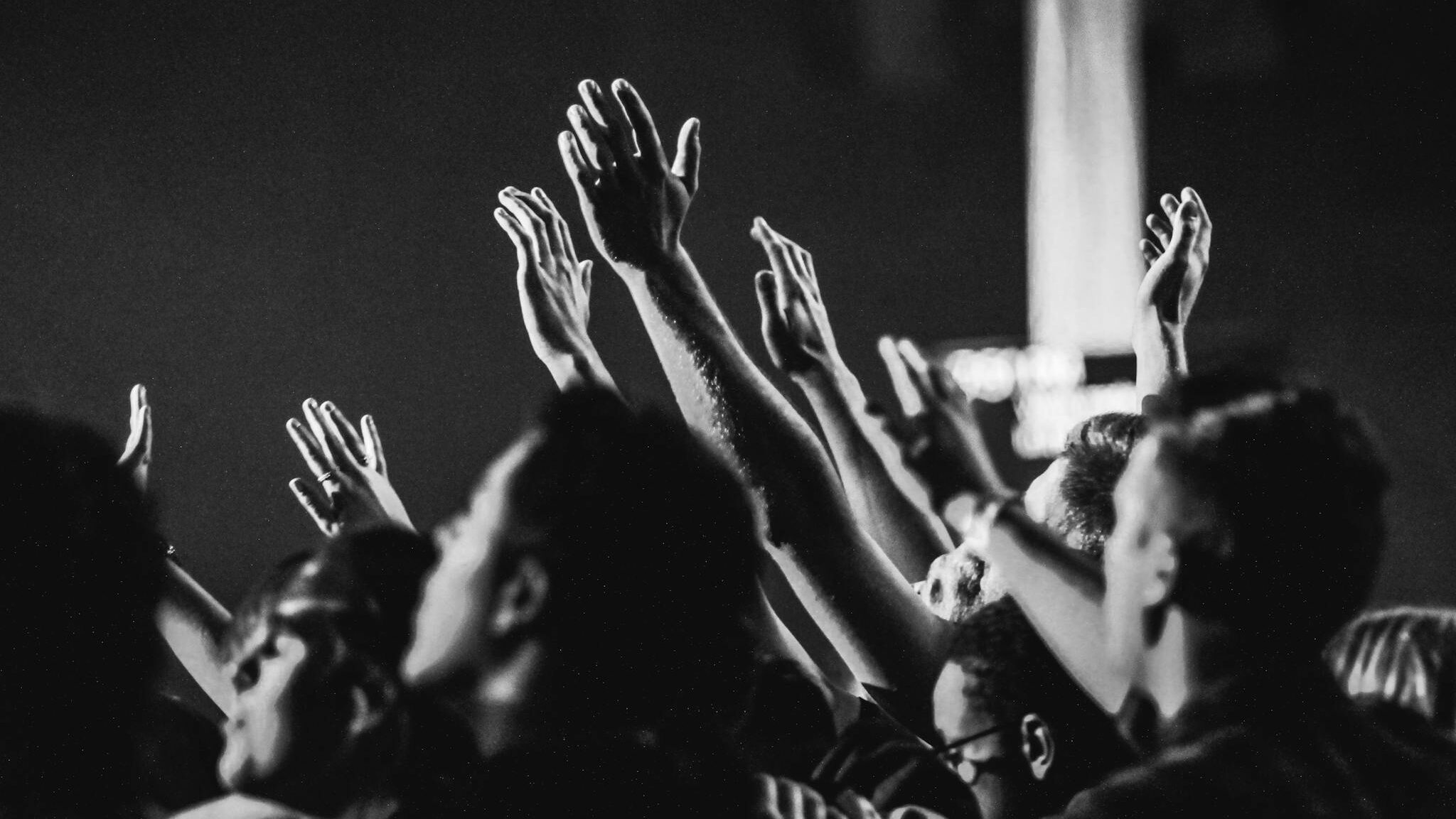 Grayscale Photo of People Raising Their Hands